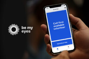 person holding a cell phone with "Be My Eyes" app on the screen 