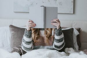 girl reading book in bed