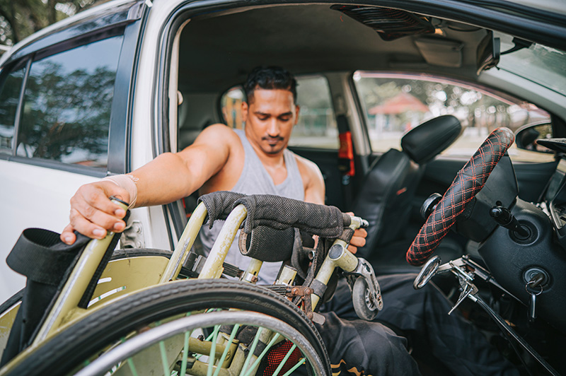 man transferring from driver's seat to wheelchair