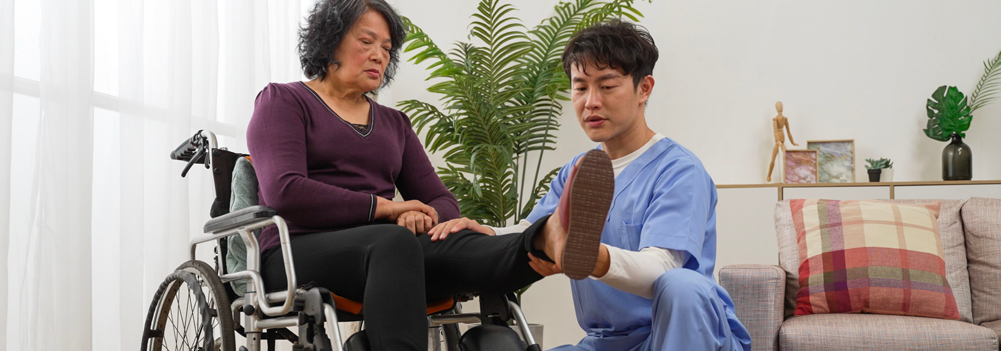An attendant helping his client exercise in her wheelchair.