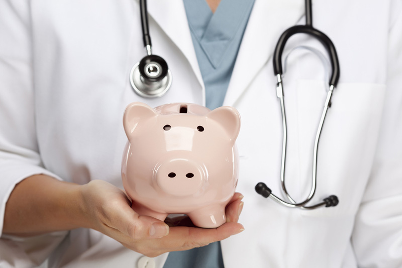 female doctor with stethoscope holding a piggy bank