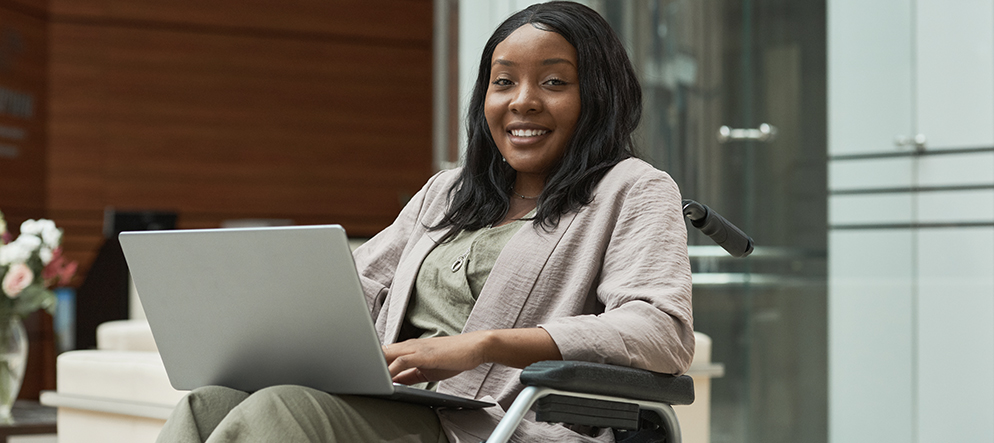 Young woman using a wheelchair and looking for a job on her laptop.