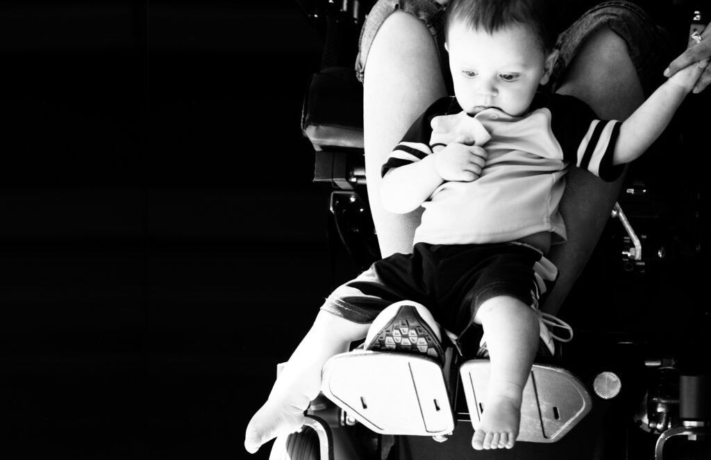 baby held by parent in a wheelchair
