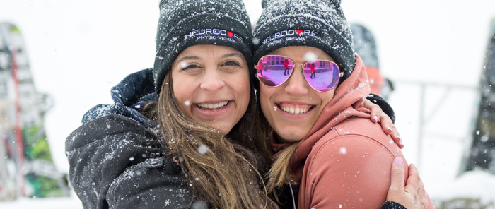 Two friends embracing in the snow at Ski Day.