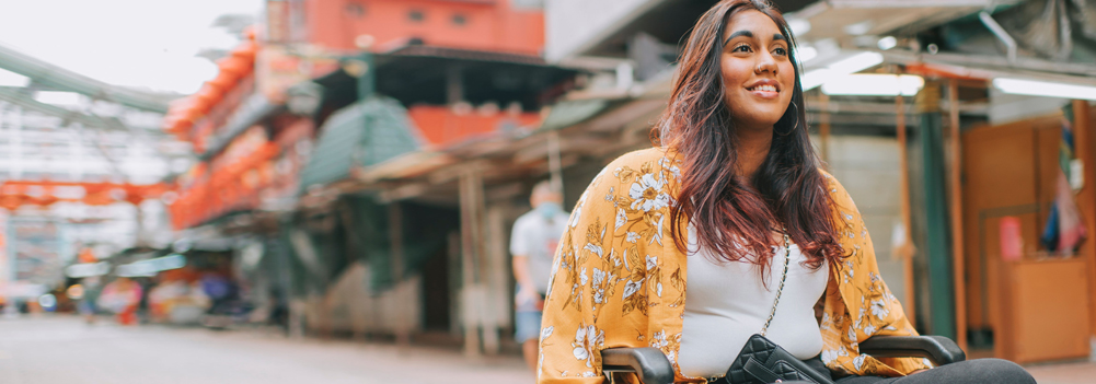 Woman wheeling down an urabn street in her wheelchair.